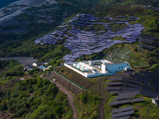 Obraz na płótnie Canvas Hillside terraced photovoltaic power station with substation facilities and solar panels