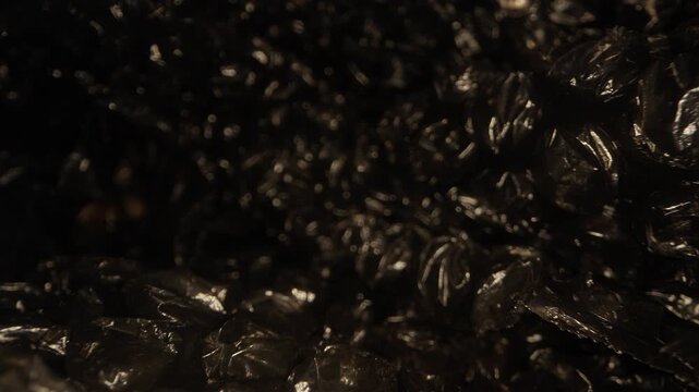 Extreme macro dolly movement over black bubble wrap packaging film with glossy plastic bubbles and soft focus highlights. Abstract background of protective packing material with cinematic lighting and