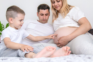 Obraz premium Pregnant woman with man at home and son family. Selective focus.