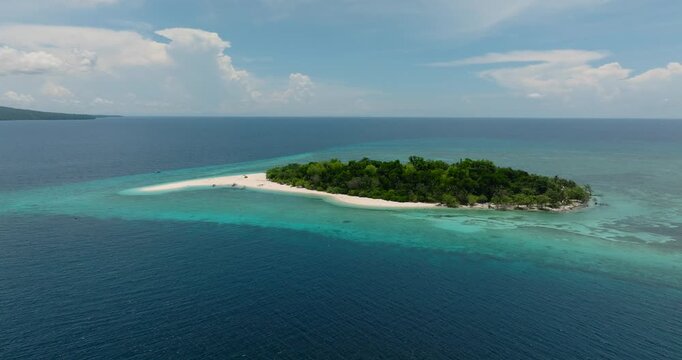 Small island with sand bar anf green trees. Mantigue Island with azure water and coral reefs. Camiguin, Philippines.