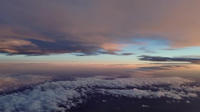 pilot&rsquo;s perspective from the cokpit of. a jet airplane flying under a layer of darkening storm cloud bathed in sunset light, with a clear sky at the background.