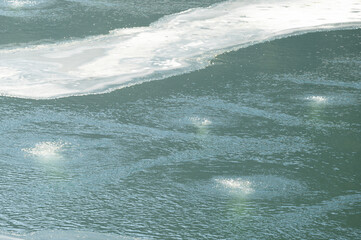 Rippling waters of a serene lake during early morning hours bring a tranquil atmosphere to the natural landscape, where icebergs melt slowly under the warm sun © Niko_Dali