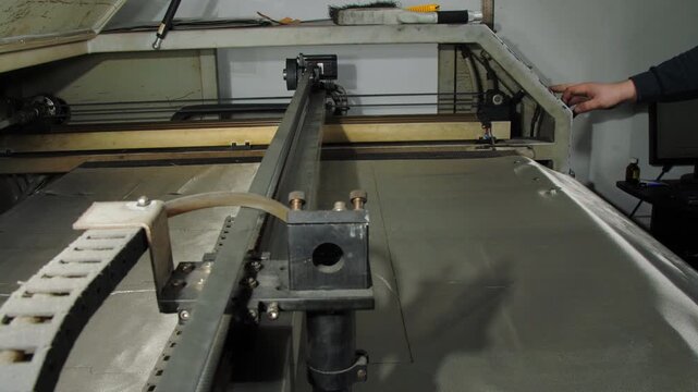 Man hand presses button to stop cutter with signal shielding fabric in manufacturing workshop closeup. Radio blocking material processing