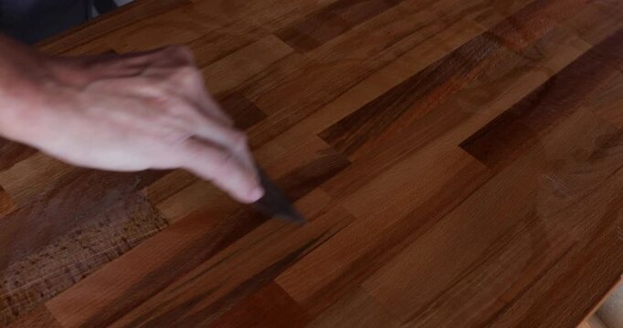 The laminated wood board is protected by tung oil, which was spread with a filler spatula
