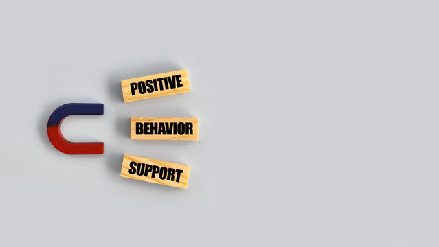 Scattered &ldquo;positive behavior support&rdquo; blocks near a magnet symbolizing challenges in maintaining positive behavior.