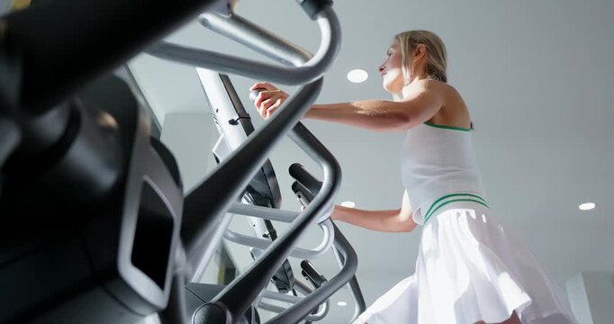 Woman Working Out on Elliptical Trainer in Gym
