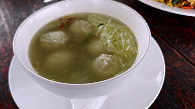 Traditional Indonesian Bakso Meatball Soup Served with Cabbage in a White Bowl