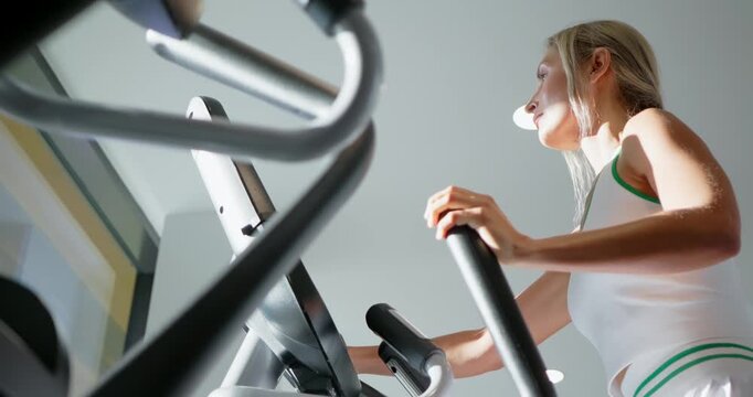 Woman Exercising on Elliptical Machine at Gym