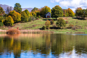 Obraz premium Calm lake surrounded by green hills and forest, beautiful natural scenery reflecting peaceful outdoor environment and fresh summer landscape.