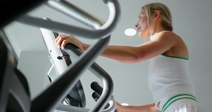 Woman Exercising on Elliptical Machine at Gym