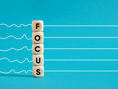 Wooden blocks with the word focus aligning clear path on blue background