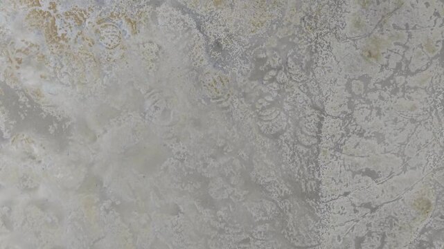 Drone footage showing coastal mudflat textures and tidal channels at low tide.