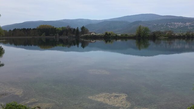 A peaceful landscape of the artificial Capodacqua Lake near Capestrano, L'Aquila province. The crystal-clear turquoise waters are surrounded by the lush vegetation of the Tirino Valley 