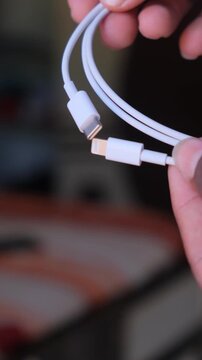 Close up of a white USB-C to Lightning charging cable held by hand