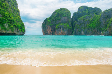 Obraz premium Tropical Maya bay beach with turquoise water, white sand and limestone cliffs on Phi Phi islands, Krabi, Thailand with nobody. Empty beach with rocks and lush greenery. Travel and tourism in Asia