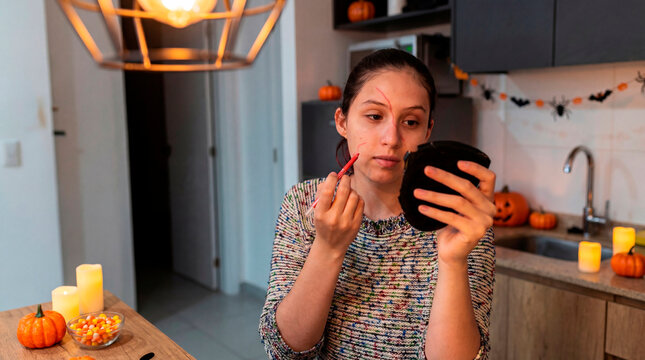 Expressive woman outlining Halloween costume makeup with pencil