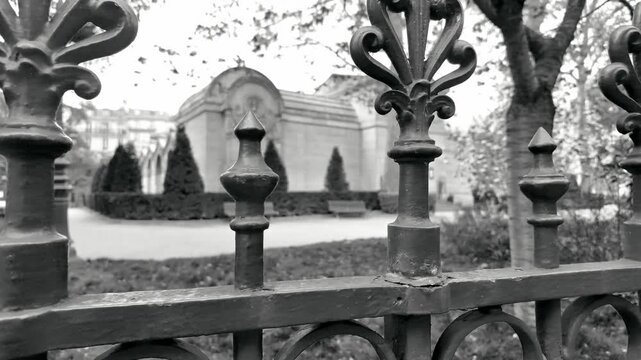 Close-up of ornate wrought iron fence finials at Square Jean-XXIII with a soft-focus background of the Parisian park.