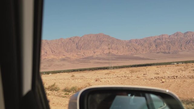 A road trip to Timna Park in Israel. A view from the car window of mountains in a desert landscape. Concept of travel and road trip.