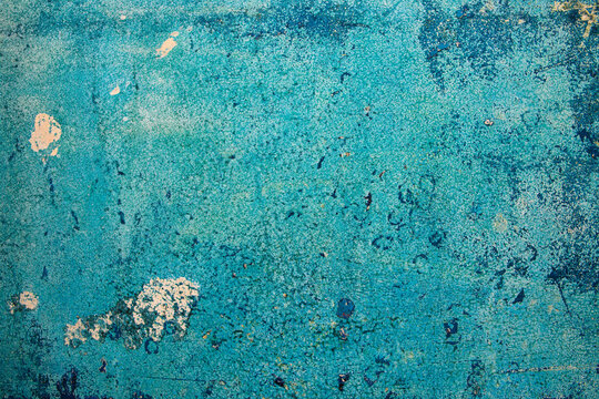 Peeling blue paint on corroded metal surface with rust stains and layered weathering creating an abstract aged pattern.