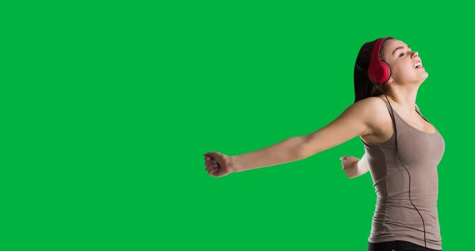 Caucasian woman wearing headphones with arms wide open against black background