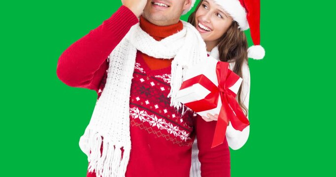 Caucasian couple wearing santa hats holding a christmas gift box against black background
