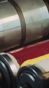 Vertical video: Press starting, roller picking up CM inks and spreading band on paper for printing