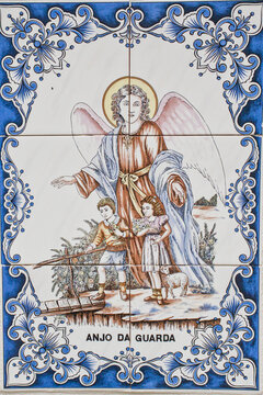 Old ceramic tiles with painted decoration of a guardian angel and playing kids,with inscription Anjo da Guarda'- Portuguese for guardian angle 
