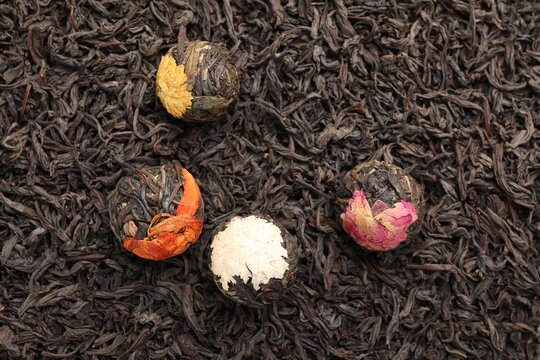 Blooming tea balls on dry leaves, top view
