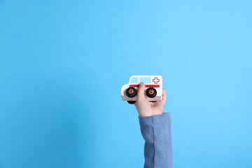 Child with toy car on light blue background, closeup. Space for text © New Africa