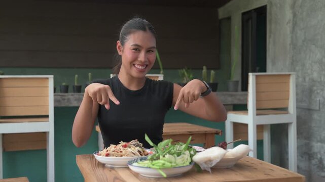 Happy Thai Woman Pointing at Traditional Isan Food Som Tum Papaya Salad on Wooden Table