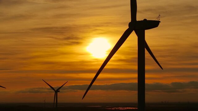 Turbine spinning in golden sunset light. Generating electricity from warm wind. Creating renewable energy with rotating blades. Delivering alternative power using environmental flow