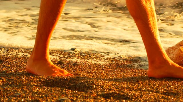 Feet beach waves washing over bare feet on a pebble shore during golden hour at sunset
