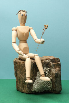 Still life with sitting wooden mannequin model, dry plant and stone. Photo with great depth of field on colored background.