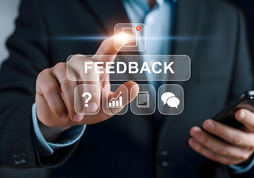 Man in suit pointing at feedback button with icons and holding phone in a blurred background