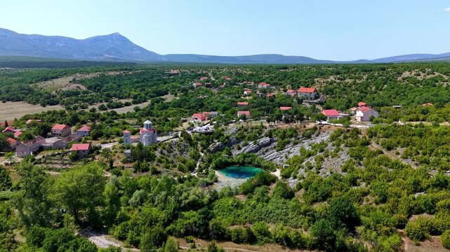 Aerial view of the Eye of the Earth, the source of the Cetina River in Croatia, featuring a small village and the Church of the Ascension