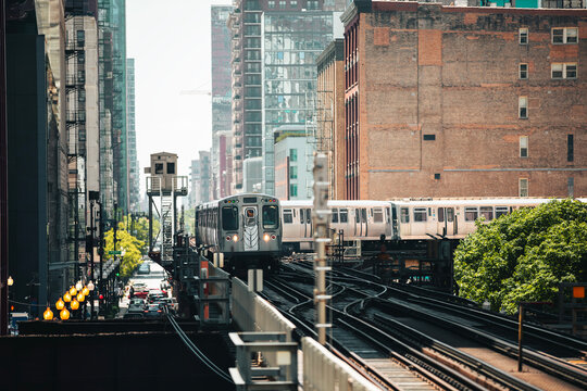 Train of public transportation arriving on elevated railway above busy street in downtown Chicago. Urban transport, city life, infrastructure, and daily commute concept.