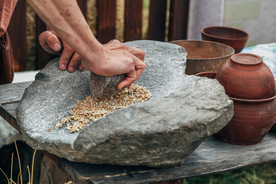 Human hand rotating an ancient stone grinding machine for smashing grains. Handmade manual equipment grind mill
