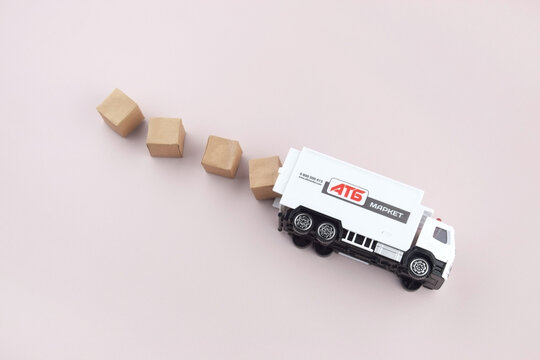 White toy truck with ATB emblem with boxes on light background, space for text.