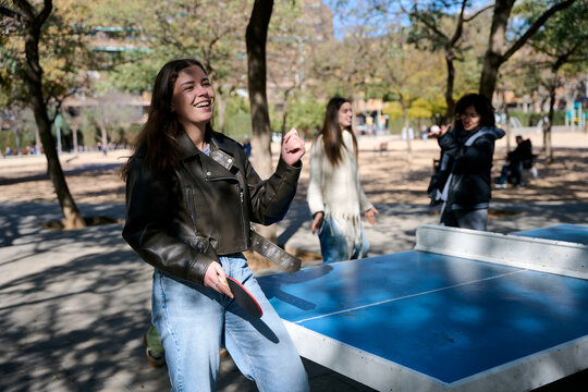 Teenage girl smiling playing table tennis outdoors