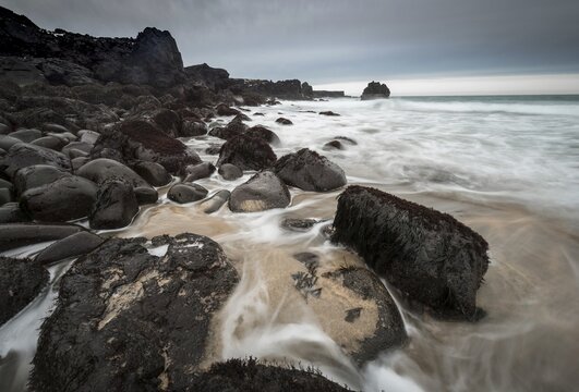 Skar&eth;sv&iacute;k Beach, sandy beach with large round black volcanic rocks, waves at the sea, bad weather, bulb exposure, West Iceland, Iceland
