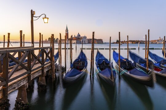 Venetian gondolas at St. Mark's Square in the evening light, blue hour, in the back monastery San Giorgio Maggiore, district San Marco, Venice, region Veneto, Italy