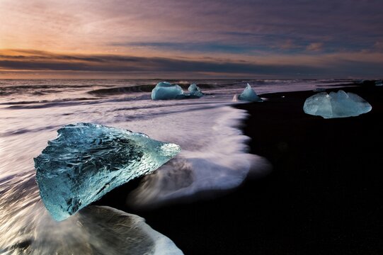 Chunks of ice on black lava sand beach at sunrise, J&ouml;kularsalon, Vik, Iceland