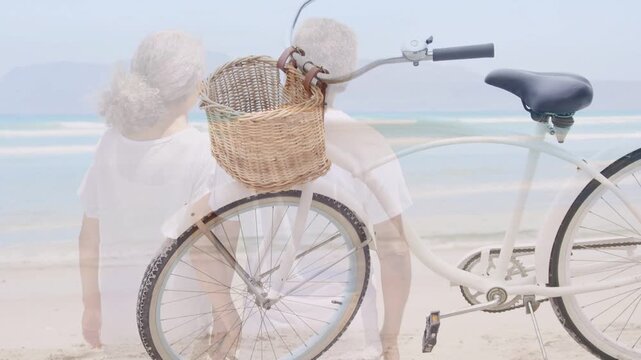 Senior pair nearing shore stopping watching sea dissolving overlay merging bike with couple travel