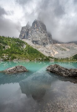 Turquoise green mountain lake, Sorapis lake, Lago di Sorapis with reflection, cloudy mountain peak Dito di Dio, Dolomites, Belluno, Italy