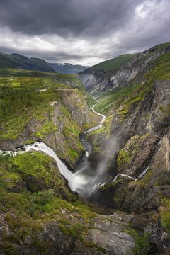 View into the river valley with waterfall V&oslash;ringfossen, river Bjoreio falls down a rock face, valley with river, Eidfjord, Norway