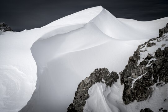 Snow cornice against a dark sky at the summit of Toreck, Riezlern, Kleinwalsertal, Vorarlberg, Austria