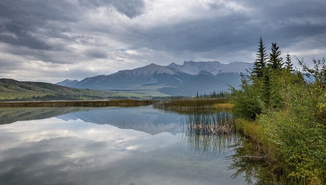 Hilly, mountainous landscape, trees reflected in a lake, in autumn, Talbot Lake, Jasper National Park, British Columbia, Canada