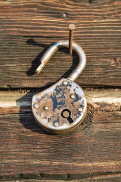 Old rusted lock hanging on a nail on a wooden wall