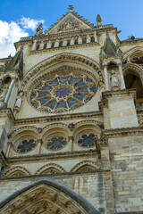 Fototapeta premium The sun illuminates the intricate stonework of this historical French masterpiece. Intricate rose windows and majestic stone statues define the facade of this cathedral.