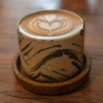 A modern coffee mug, containing a Flat white, with an intricate design on the top, served in a coffee shop on the Island of Java, Indonesia